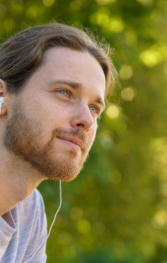 Ung man utomhus lyssnar på musik