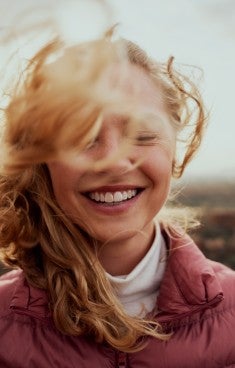 Porträttbild på leende kvinna med ansiktet delvis täckt av hår