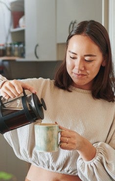 Kvinna häller upp kaffe i en kopp