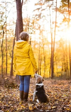 Kvinna med hund i skogen på hösten