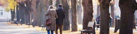 Medelålders par vandrar bland höstlöv i park