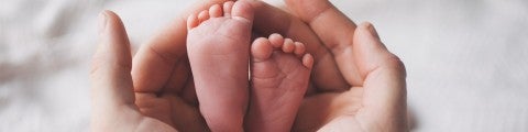 Fötter från nyfödd vilar i händer
