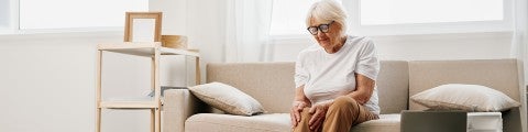 Äldre kvinna sitter i soffa 