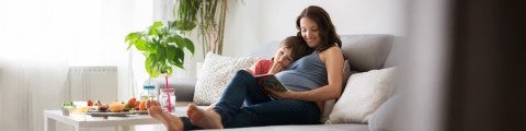 Gravid kvinna sitter med sin son i soffan