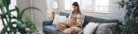 Gravid kvinna sitter i soffan