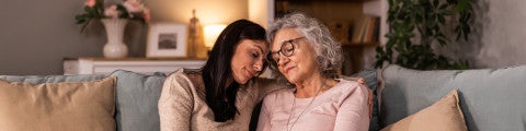 Em mamma och dotter kramas i soffa