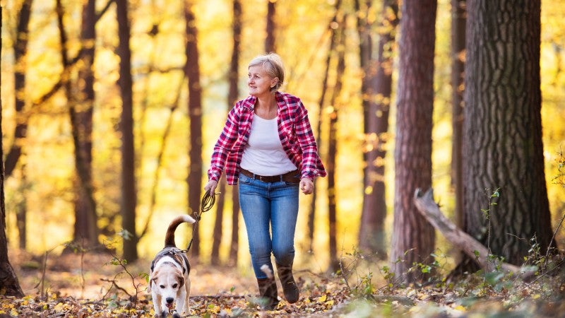 Äldre kvinna med hund i skogen