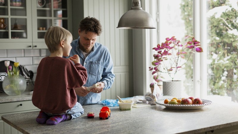 Pojke och pappa äter mellis i köket