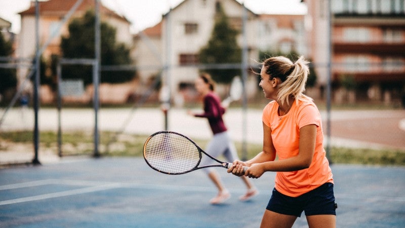 två kvinnor spelar tennis