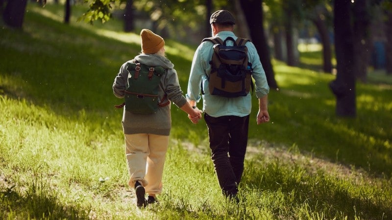 Par bakifrån som går hand i hand i naturen